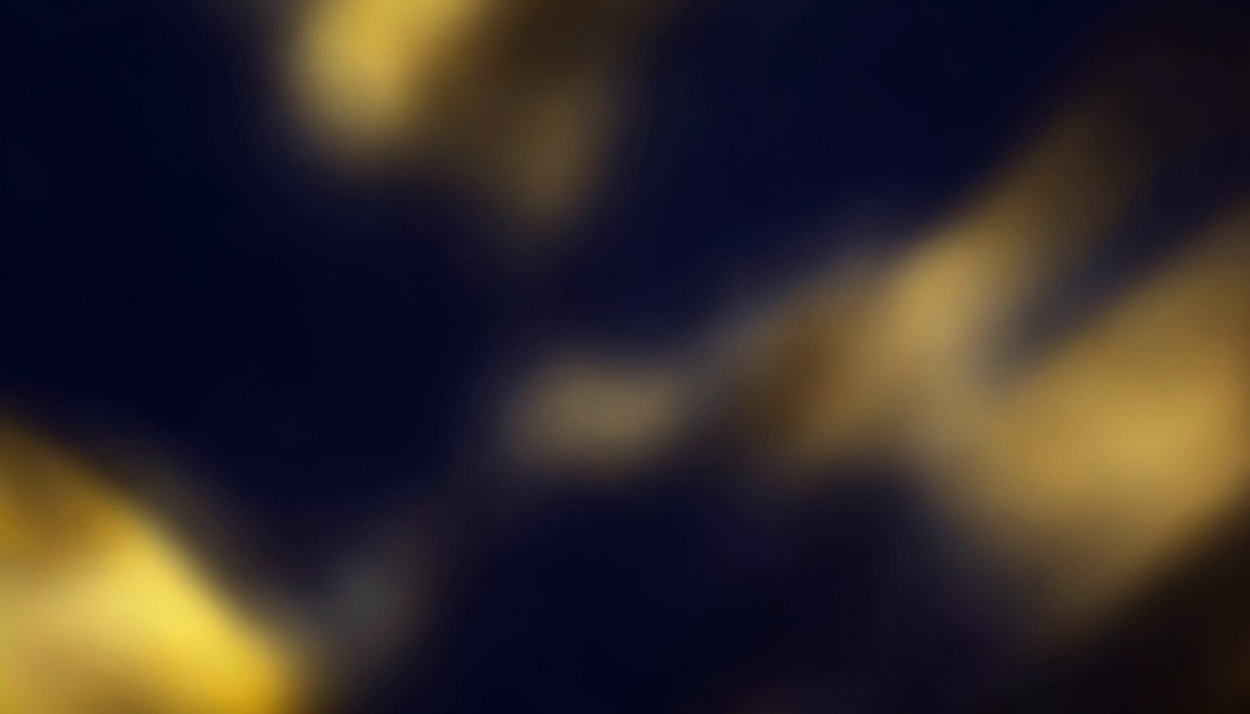 Warm abstract backdrop with deep navy and golden yellow tones, evoking a conference atmosphere